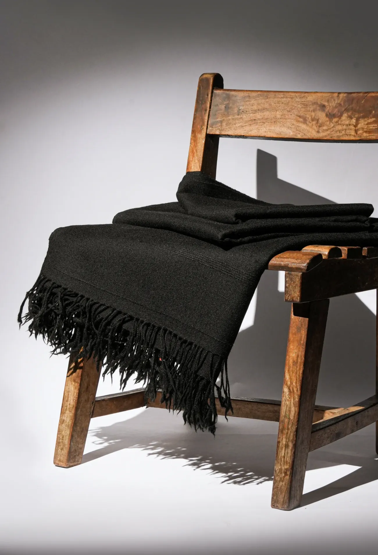 Black wool shawl draped over a wooden chair