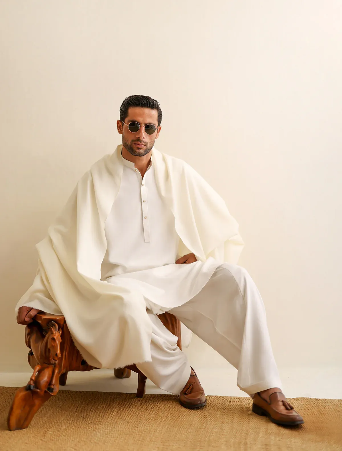 Man in a white shawl seated on a wooden chair