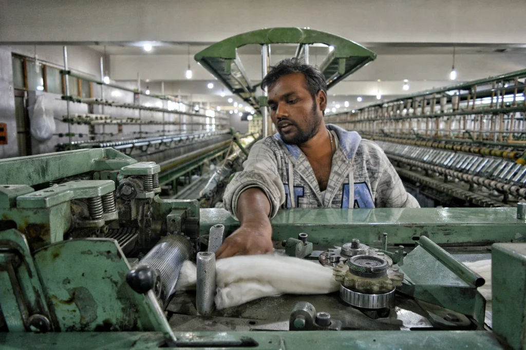 Worker operating a spinning machine at the MK Shawls mill